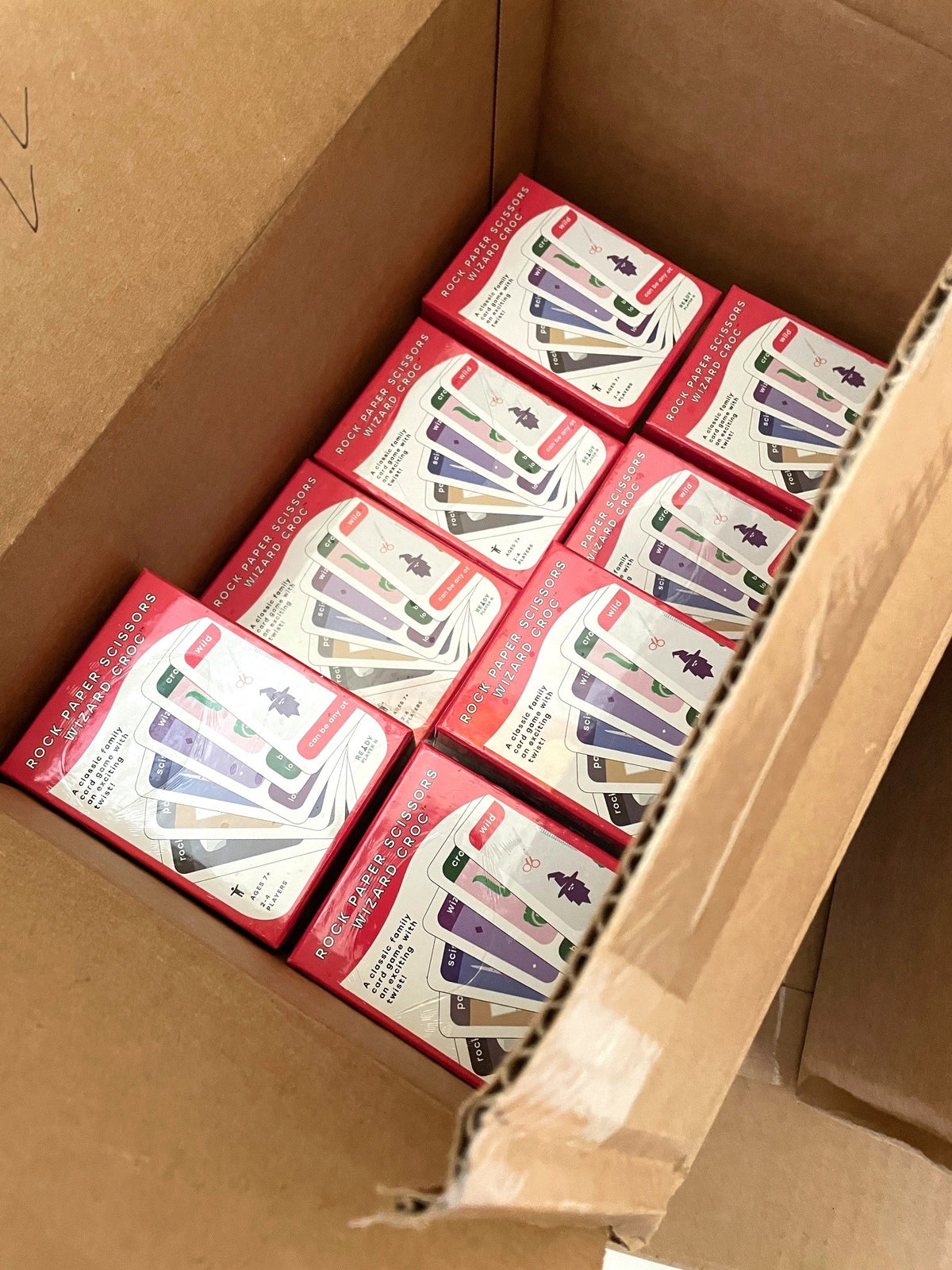 Open case, removed from pallet, showing multiple boxes of the card game, as sent by the printer.
