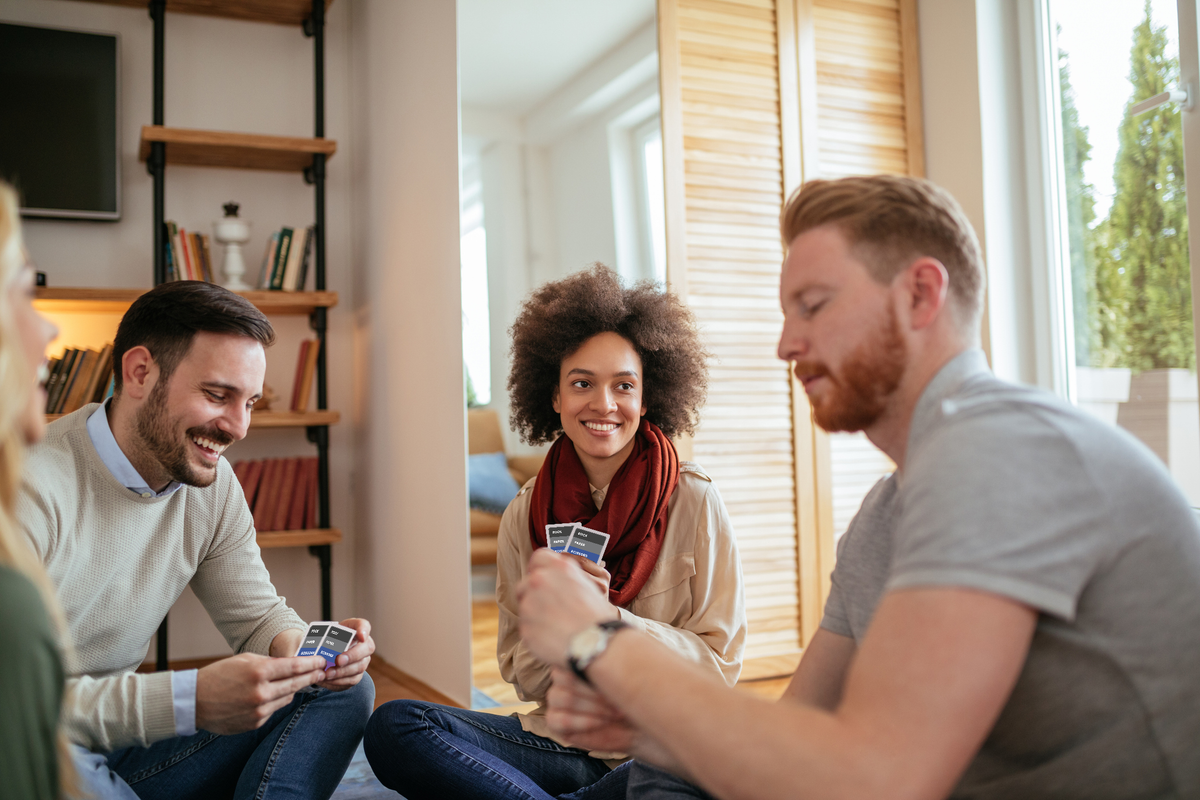 Adult friend group playing RPSWC in an apartment setting to emphasize that the game is for both adults and kids.