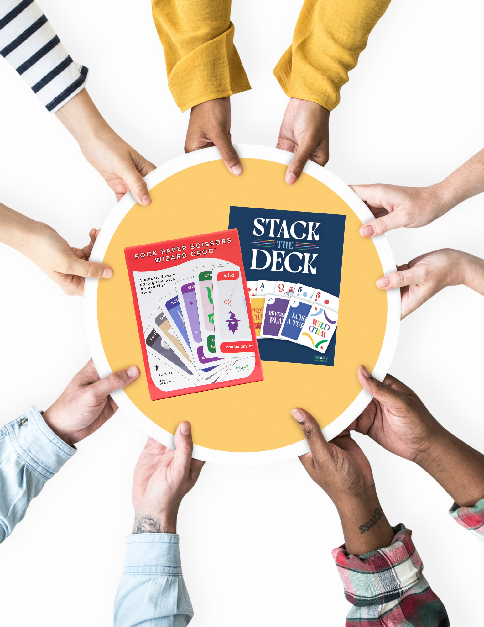 Hands reaching towards a yellow plate with 'Stack the Deck' and 'Rock Paper Scissors Wizard Croc' card game packaging in the middle.