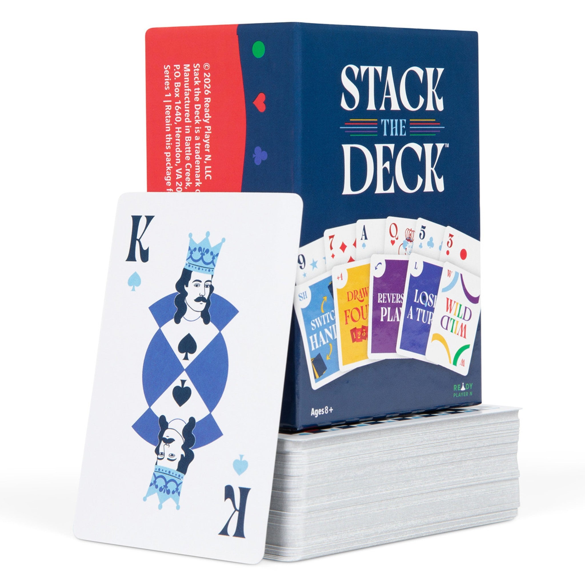  King of Spades playing card leaning against a colorful Stack the Deck box that's on top a pile of cards