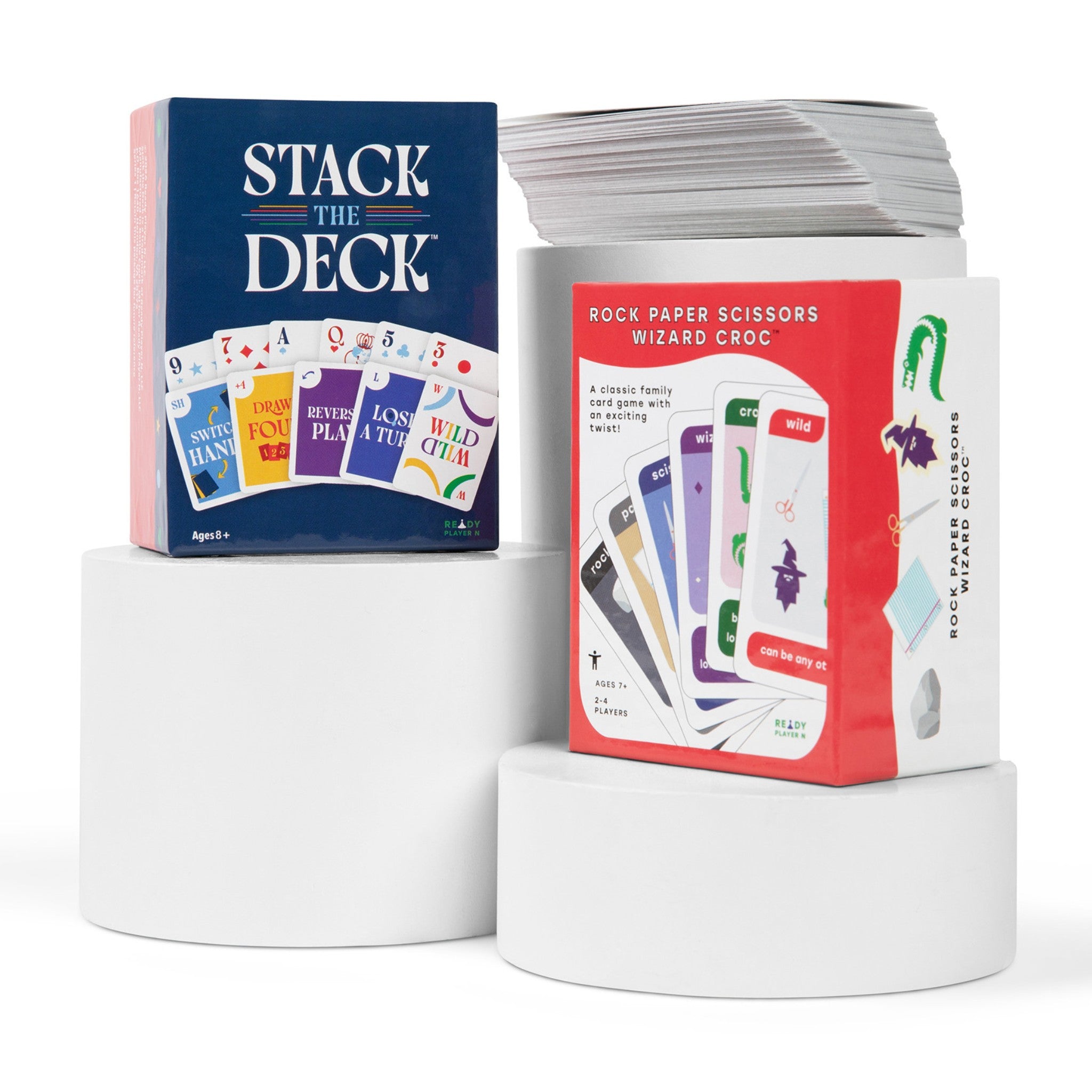 Card game packaging with 'Stack the Deck' and 'Rock Paper Scissors Wizard Croc' on white stands.